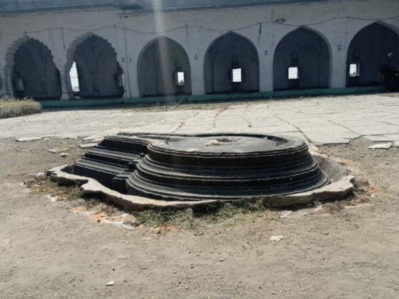 Remnant of a Hindu temple Yoni pedestal inside the courtyard of a dargah at Khuldabad, symbolizing the sacred past beneath the site.