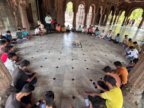 Young volunteers from Ramdoot Restores engaged in a group prayer and planning session inside a historic temple