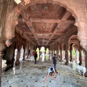 Ramdoot Restores volunteers cleaning the marble floor of a historic temple hall as part of a restoration drive.