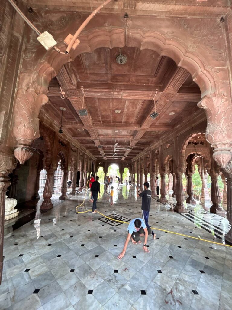 Ramdoot Restores volunteers cleaning the marble floor of a historic temple hall as part of a restoration drive.