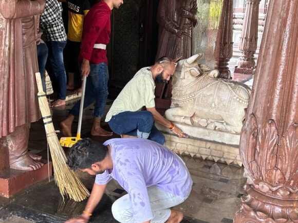 Ramdoot Restores volunteers cleaning temple floor and sacred Nandi statue during restoration seva.