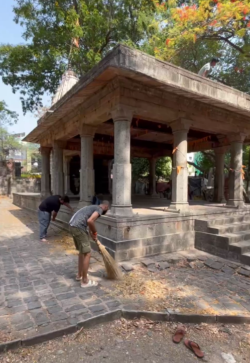 Volunteers from Ramdoot Restores sweeping the surroundings of an ancient temple as part of revival seva.