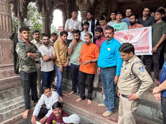 Group of Ramdoot Restores volunteers gathered at a temple site with banners promoting temple revival work