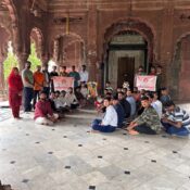 Ramdoot Restores volunteers sitting and standing inside a historic temple during a restoration gathering, holding banners.