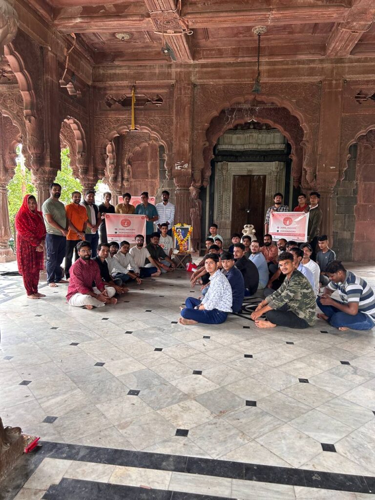 Ramdoot Restores volunteers sitting and standing inside a historic temple during a restoration gathering, holding banners.