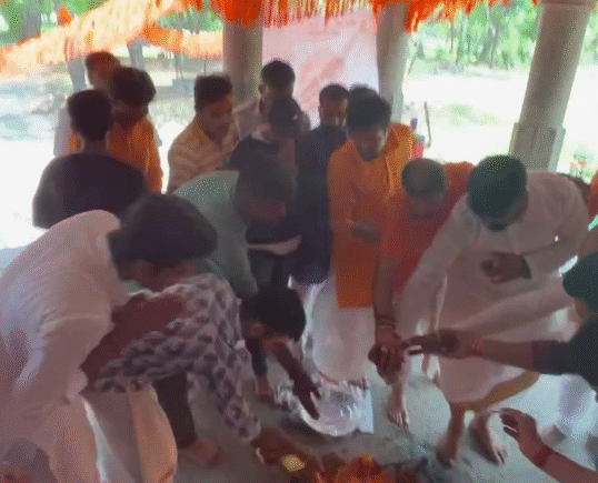 Devotees gather around a sacred fire performing havan rituals during a temple restoration ceremony.