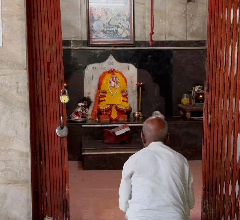 Elderly devotee praying inside a Hanuman temple.