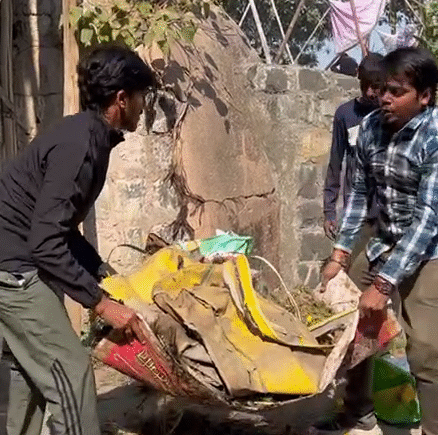 Volunteers carrying collected waste and debris in a sack during the cleaning drive at Gangour Ghat, Indore, organized by Ramdoot Restores.