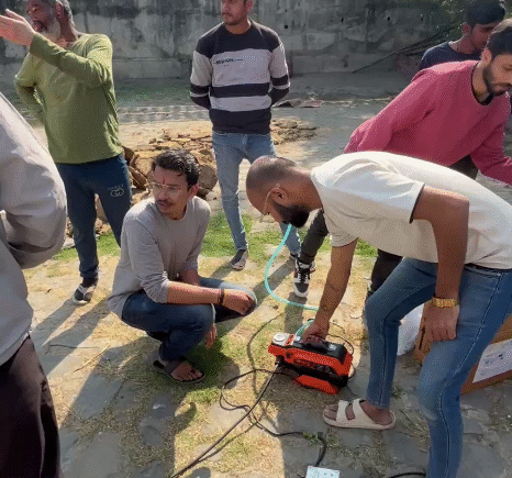 Volunteers from Ramdoot Restores operating a jet spray/pump machine to clean temple walls and premises during restoration work.